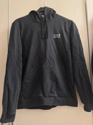 EA7 Emporio Armani tröja  - EA7 hoodien är i färgen dark blue med silverlogga, storlek M.  Använd max 2 gånger och är i mycket bra skick. Inga hål, inga fläckar och inga synliga tecken på användning.  Nypris ca 500 kr. Säljs då den inte kommer till användning.  Katt finns i hemmet.  #ea7 #emporioarmani #hoodie #armani
