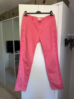 Rosa chinos från Odd Molly - Säljer ett par unika rosa chinos från Odd Molly med raka ben och snygga broderade detaljer längs sidorna. Jeansen har normal midja och stängs med knapp och dragkedja. Perfekta för dig som vill sticka ut lite extra! Från märket Odd Molly i storlek 3 som enligt deras storlekguide motsvarar en storlek L. Mycket fint skick, jag hittar inga synliga anmärkningar eller defekter. 