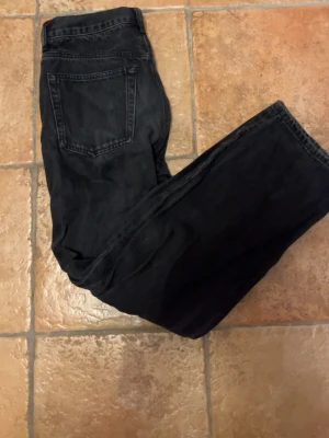 WEEKDAY galaxy loose straight jeans - Säljer ett par svarta jeans med rak passform och klassisk femficksdesign. Jeansen har en något tvättad look och är tillverkade i denim. Perfekta för dig som gillar en enkel och stilren stil.