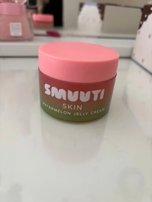 Smuuti Skin Watermelon Jelly Cream - En söt burk med Smuutis Watermelon Jelly Cream. Krämen har en geléliknande konsistens och kommer i en rund burk med rosa lock och grön-rosa färg på förpackningen. Perfekt för dig som gillar fräscha och återfuktande hudvårdsprodukter. Är ca halva kvar av den 