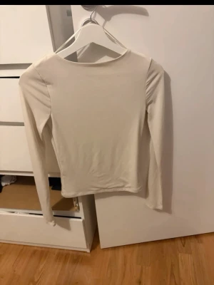 Ljusbeige långärmad topp med öppen rygg - Säljer en stilren ljusbeige långärmad topp med en öppen rygg. Toppen har en enkel, tight passform som passar perfekt till jeans eller kjol. 