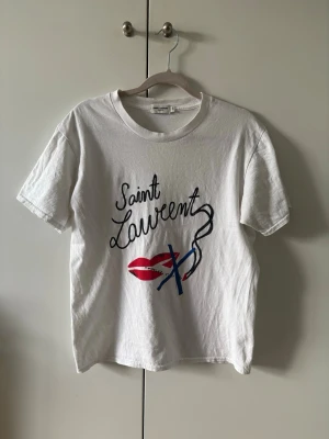 Vit Saint Laurent t-shirt - Säljer min vita Saint Laurent t-shirt i storleken S (passar XS). T-shirten är i mycket fint skick och sparsamt använd. Säljes då den är för liten. Saint Laurent kort tillkommer.
