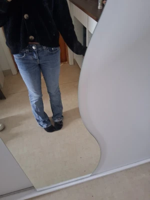 Ljusblå raka jeans med låg midja - Säljer ett par ljusblå jeans med låg midja och raka ben. Jeansen har klassisk femficksdesign och stängs med knapp och dragkedja. Perfekta för en avslappnad och trendig look.