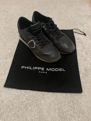 Philippe Model sneakers - Snygga blåa sneakers från Philippe Model med detaljer i mocka och läder. Skorna har en vit sula och den ikoniska sköldloggan på sidan. Perfekta för dig som gillar stilrena och exklusiva sneakers med en sportig touch.