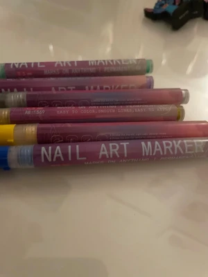 Färgglada Nail Art Marker pennor - Säljer ett set med Nail Art Marker pennor i flera färger som blå, gul, grön, lila och rosa. Perfekta för att skapa kreativa och detaljerade nageldesigner. Pennorna har smidig form och är enkla att använda för både nybörjare och proffs.