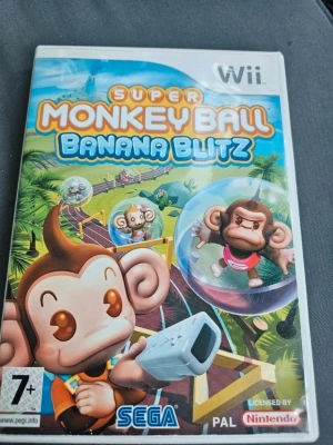 Super Monkey Ball Banana Blitz Wii - Super Monkey Ball Banana Blitz till Nintendo Wii. Färgglatt och roligt partyspel där du styr apor i bollar genom olika banor och minispel. Omslaget har tecknade apor och bananer, och spelet är licensierat av Nintendo. Perfekt för dig som gillar utmanande och fartfyllda spel.