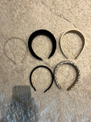 Fem snygga diadem i olika stilar - Säljer ett paket med fem diadem: ett tunt silverfärgat med pärlor (tror de är från Ur&penn), ett svart vadderat (osäker vart de är ifrån), ett vitt vadderat (ifrån SHEIN), ett svart med glittrande stenar (ifrån shein eller glitter är osäker!), och ett vitt med svart rutmönster (ifrån SHEIN). Perfekta accessoarer för att lyfta din look och matcha olika outfits! Skriv privat om ni har frågor eller funderingar🤎
