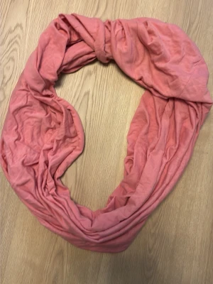 Korall tubscarf i mjukt tyg 100% bomull - En enkel och snygg rosa/korall tubscarf i mjukt, tunt tyg. Sjalen är rundsydd och har en avslappnad look. Perfekt att slänga på sig för att addera färg till din outfit.
