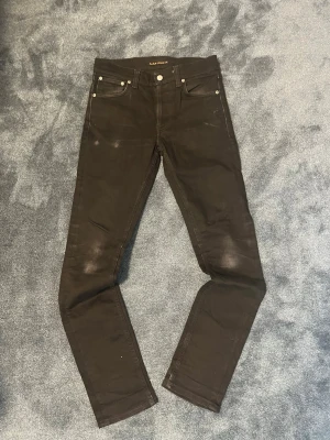 Nudie Jeans lean dean  - Snygga svarta skinny jeans från Nudie Jeans med klassisk femficksmodell och silverfärgade nitar. Jeansen har en smal passform och är tillverkade i stretchigt denimtyg för extra komfort. Perfekta för en stilren och modern look.