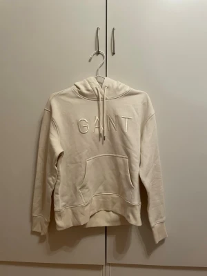 Hoodie från GANT - Stilren hoodie från Gant i off white/beige. Använd ett fåtal gånger så i mycket bra skick. Pris kan diskuteras.