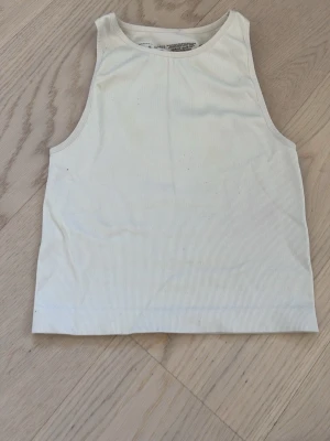 Vit ribbad linnetopp från Primark - Säljer en enkel och fräsch vit ribbad linnetopp från Primark. Toppen är ärmlös och har en klassisk rund halsringning. Perfekt till sommaren och lätt att matcha med allt. Materialet är mjukt och stretchigt för skön passform.