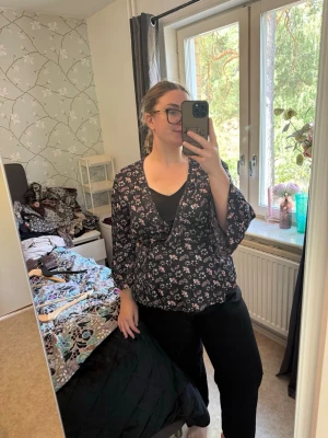 Svart blommig omlottblus - Säljer en svart omlottblus med små rosa och vita blommor. Blusen har trekvartsärm och ett löst, flowy fall. Perfekt för dig som gillar en avslappnad men ändå söt stil. Materialet känns lätt och luftigt. Från märket Odd Molly i storlek 4 som enligt deras storlekguide motsvarar en storlek L/XL. Mycket fint skick, jag hittar inga synliga anmärkningar eller defekter. 