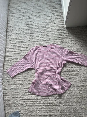 Rosa och vit randig topp Cappuccini - Säljer en söt rosa och vit randig topp från Cappuccini i storlek XXL. Toppen har rund halsringning och trekvartsärm. Perfekt för dig som gillar en avslappnad och bekväm stil.