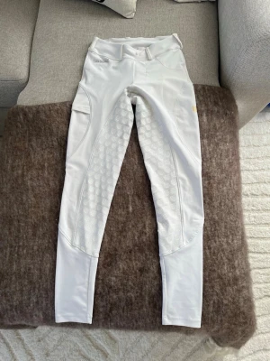 Vita Maya Delorez ridbyxor - Säljer mina vita Maya Delorez Performance Breeches med helskodd i silikonmönster för extra grepp. De har medelhög midja med hällor för bälte och mobilficka på sidan. Materialet är stretchigt. Få med ett dekorativ hårnät på köpet. Byxorna har nypris 1 199, prutmån finns. För mer information se Maya Delorez hemsida. 