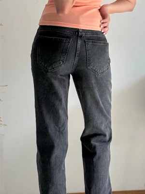 Midwaist svarta raka jeans - Säljer ett par svarta raka jeans med medelhög midja och klassiska bakfickor. Jeansen har en avslappnad passform och är tillverkade i denim med lätt tvättad look. Perfekta för en chill och trendig stil.