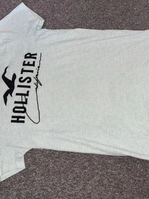 Hollister t-shirt  - Snygg t-shirt från Hollister med svart logga och text på framsidan. Klassisk rund halsringning och korta ärmar. Tillverkad i 100% bomull för en mjuk och bekväm känsla. Perfekt till jeans eller shorts för en avslappnad stil. Pris kan diskuteras