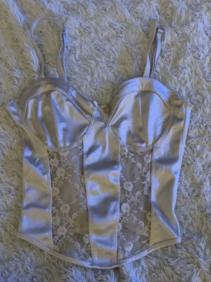 Beige satin nattlinne med spetsdetaljer - Snyggt nattlinne i beige satin med genomskinliga spetspaneler framtill. Justerbara axelband och formpressade kupor ger en feminin siluett. Perfekt för dig som vill känna dig extra fin när du slappar hemma. Finns inte att köpa längre.❤️