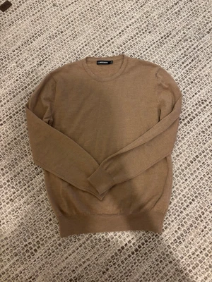 Beige stickad tröja J.Lindeberg - J.Lindeberg stickad tröja i brun/beige färg 🤎 Stilren och klassisk modell med rund hals och diskret J.Lindeberg-logga på bröstet. Snygg att bära både till jeans och chinos. Tröjan är i fint skick och har en tidlös färg som passar till det mesta. 📏 Storlek: L 🎨 Färg: Brun/beige 🏷️ Märke: J.Lindeberg ✨ Fint skick Skickas snabbt och välpackad! 