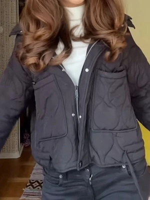 Svart quiltad jacka med dragkedja - Snygg svart quiltad jacka med dragkedja och knappar framtill. Jackan har stora fickor och en croppad passform som ger en trendig look. Perfekt för lager på lager och funkar till många olika stilar.