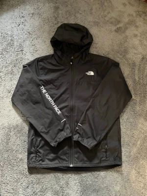 The North Face WindWall jacka – svart - Säljer en The North Face WindWall jacka i svart. Storleken är boys/Junior XL, vilket sagt i vuxen storlek är XS men känns snarare som S i passform. Väldigt fint skick, sparsamt använd och utan skador/fläckar. Skriv om du har frågor🫵, och pris går såklart att diskutera!