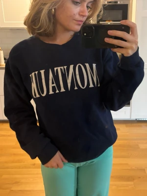 Mörkblå sweatshirt med tryck - Mörkblå sweatshirt med vit text 'MONTAUK' framtill. Tröjan har rund halsringning, långa ärmar och ribbade muddar vid ärmslut och nederkant.