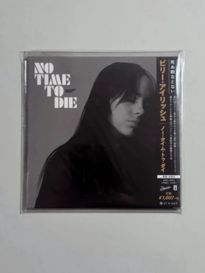 Billie eilish No Time To Die 007 cd 2020 - Säljer en samlarutgåva med titeln 'No Time To Die 007'. Omslaget är svartvitt med porträtt och japansk text längs kanten. Fyrkantig form, troligen papper eller kartong, perfekt för James Bond-fans eller samlare.