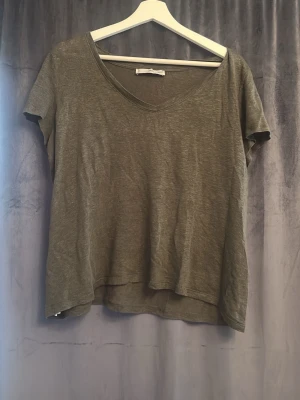 Grön v-ringad t-shirt - En enkel grön t-shirt med v-ringning och korta ärmar. Modellen är lite lösare och har en avslappnad passform. Perfekt till jeans eller shorts för en chill look.
