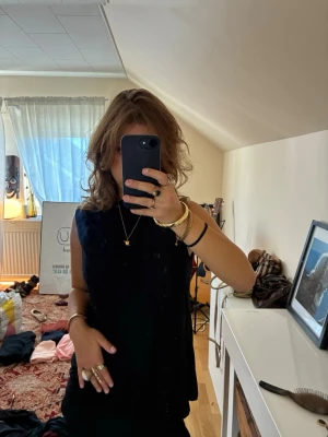 Svart ärmlös linnetopp - Snygg svart ärmlös linnetopp med rund halsringning. Perfekt att styla med smycken och accessoarer för en clean look. Toppen har en enkel och tidlös design som passar till många olika outfits.
