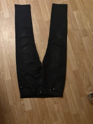 Svarta Levis 502 30 32 - Säljer ett par levis jeans med rak passform och klassisk femficksdesign. Jeansen har bälteshällor och silverfärgade nitar vid fickorna. Materialet ser ut att vara denim med en matt finish. Perfekta till en avslappnad stil. Stl W30 L32