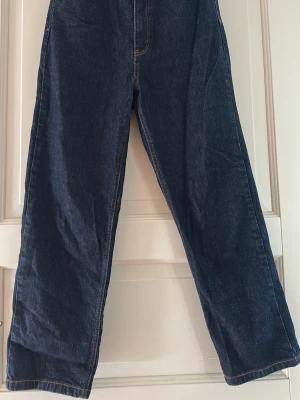 Mörkblå raka jeans Carin Wester 38 modell Claudia  - Säljer ett par mörkblå jeans från Carin Wester i rak modell. Jeansen har hög midja, klassiska kontrastsömmar och är tillverkade i ett kraftigt denimtyg. Perfekta för en avslappnad och trendig look. Något små i storleken. 