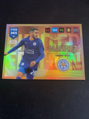 FIFA 365 Limited Edition Mahrez-kort - Säljer ett FIFA 365 Limited Edition samlarkort med Mahrez från Leicester City FC. Kortet har en glansig, holografisk yta med färger i blått, guld och regnbågseffekt. Perfekt för dig som gillar fotboll och samlarkort.