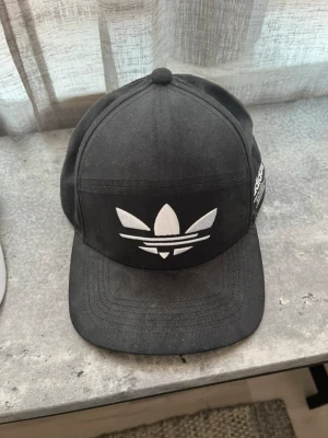 Adidas keps  - Oanvänd Adidas keps, vet ej storlek. stått i en hylla så är dammig. 