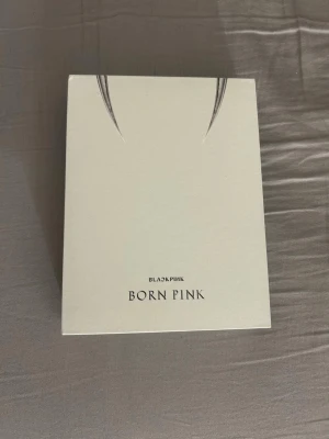 BLACKPINK Born Pink album - Säljer ett BLACKPINK Born Pink album med vit och stilren framsida och tryckt låtlista på baksidan. Albumet är i bokformat och innehåller åtta låtar. Perfekt för dig som gillar K-pop och samlar på BLACKPINK-merch. Albumet innehåller en photocard, två polaroids, lyrics, två bilder, en photobook och en cd