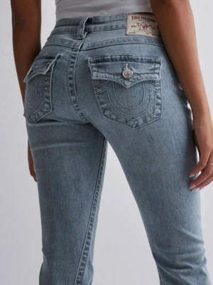Bootcut jeans från True Religion - Säljer ett par ljusblå bootcut jeans från True Religion med klassiska kontrastsömmar och snygga fickdetaljer bak. Jeansen låg  midjade och är tillverkade i denim med lätt stretch för skön passform.