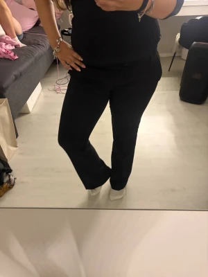 Svarta utsvängda kostymbyxor - Säljer ett par svarta kostymbyxor med utsvängda ben och klassisk passform. Byxorna har normal midja och diskreta fickor framtill. Perfekta för en stilren look och passar till många olika outfits.