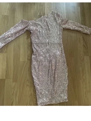Glittrig ljusrosa paljettklänning - Säljer en glittrig ljusrosa klänning med paljetter över hela plagget. Klänningen har lång ärm, kroppsnära passform och går ner till knäna. Passar om man vill sticka ut på nästa events!