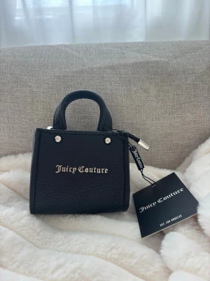 Juicy Couture - Stilren svart minihandväska från Juicy Couture. Väskan har två små handtag, silverfärgade detaljer. Köpt på raglady i Helsingborg! Nypris 699kr 