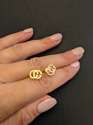 Guldiga GG örhängen - Snygga små örhängen i guldfärgad metall med den klassiska GG-loggan. Perfekta för dig som gillar stilrena accessoarer med en lyxig touch. Stiftmodell som sitter bekvämt på örat och passar till många olika looks.