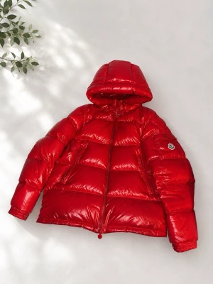 Röd glansig dunjacka med huva - Säljer en röd, glansig dunjacka från Moncler med huva och dragkedja framtill. Jackan har två sidofickor med dragkedja och en Moncler-logga på ärmen. Puffig modell som håller dig varm under kalla vinterdagar. Finns några fläckar men går att ta bort och spänn grejen är paj men går att fixa med 