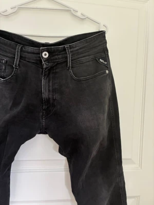Svarta Replay Ambas jeans med tvättad look - Snygga svarta jeans från Replay med tvättad finish och klassisk femficksmodell. Jeansen har raka ben, silverfärgad knapp och diskret Replay-logga vid fickan. Perfekta för en trendig och avslappnad stil.