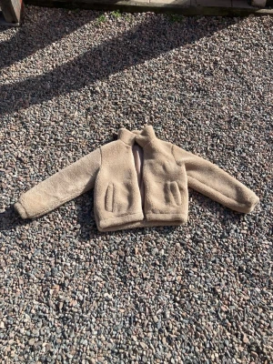 Beige teddyjacka med hög krage, strl 158/164 - Säljer en beige teddyjacka med hög krage och två fickor framtill, i storlek 158/164(känns dock mer som strl 36). Jackan har en rak passform och är gjord i fluffigt teddy-material som håller dig varm. (Se bild 5 för att se jackan på). Perfekt för dig som vill ha en varm och bekväm jacka till hösten eller vintern. Den är i mycket bra skick, finns inga defekter eller hål osv någonstans. Säljes pga för liten🤩☺️