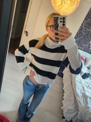 Randig stickad polotröja - Säljer en stickad polotröja med breda svarta och vita ränder. Tröjan har en lös passform, långa ärmar och hög krage. Perfekt för dig som gillar en avslappnad och trendig stil. Materialet känns mjukt och bekvämt.storlek 158/164 från Lindex🤗💗