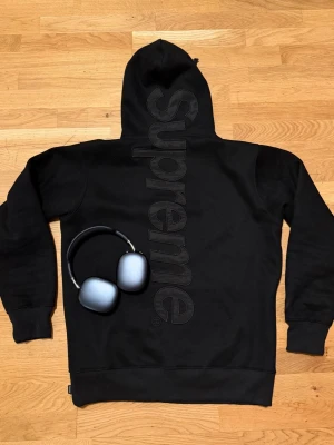 Svart Supreme hoodie - Svart hoodie från Supreme med stor, svart Supreme-logga vertikalt på ryggen. Klassisk huva. Perfekt till höst som är runt hörnet. Aldrig använd