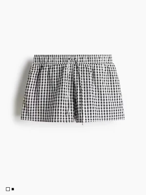 Rutiga shorts med snörning - Säljer ett par svartvita rutiga shorts med snörning i midjan. De har en avslappnad passform och är tillverkade vävd bomull, perfekta för varma dagar eller pyjamas shorts. Har en liten slits på sidorna. 