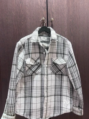 Beige och olivgrön rutig overshirt - Snygg overshirt i vit och svart rutigt mönster. Två bröstfickor med lock och knappar framtill. Skön, lite tjockare material som passar perfekt till lager på lager. Klassisk krage och långa ärmar med knapp vid ärmslutits been used 2 times. ska hämtas från kungsholmen. tar emot swish!.