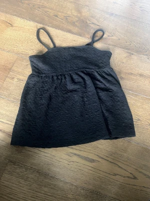 Svart linnetopp från Lindex - Snygg svart linnetopp från Lindex med tunna axelband och lätt strukturerat tyg. Perfekt för varma dagar och enkel att matcha med olika stilar. Passar dig som gillar en enkel men trendig look.🩷