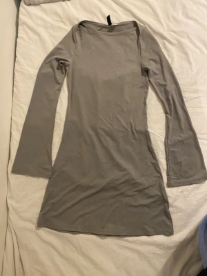 Beige långärmad kortklänning - En enkel och stilren beige klänning med lång ärm och rak passform. Klänningen är kort och har en mjuk, stretchig känsla som gör den bekväm att bära. Perfekt för dig som gillar minimalistisk stil.