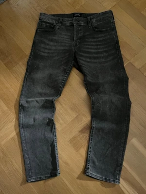 Svarta slim fit jeans med tvättade detaljer - Säljer ett par grå/svarta slim fit jeans med snygga tvättade detaljer och klassisk femficksmodell. Jeansen har raka ben och en trendig tvätt stil. Perfekta till vardagsstilen och passar till det mesta.