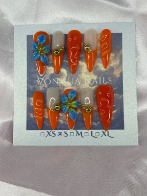 Tangerine 🍊(S);Medium Stiletto - Snygga handgjorda och unika press-on naglar i orange och nude med en medium lång stilettoform. Några naglar har 3D-blommor i blått och gult samt guldfärgade pärldetaljer. Perfekt för dig som vill sticka ut med färg och cool design.S: 15 mm, 11,5 mm, 12 mm, 11 mm, 9 mm 