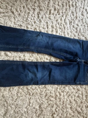 Mörkblå raka jeans - Snygga mörkblå jeans med bootcut och kontrastsömmar. Klassisk femficksmodell med detaljerade bakfickor. Perfekta till en avslappnad stil och passar till det mesta. Tillverkade i mjukt denimtyg för skön känsla.